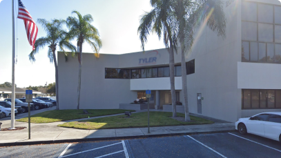 Modern office building with the "Clearwater" sign, featuring a flagpole with an American flag, under a clear blue sky with a lens flare from the sun.